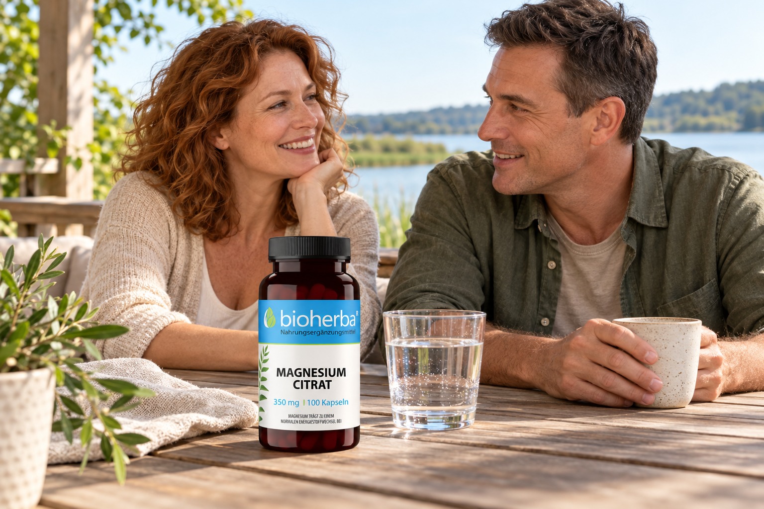 Bioherba Magnesium Citrat mit einem erwachsenen Paar auf einer Terrasse am See – KI-generierte Lifestyle-Darstellung